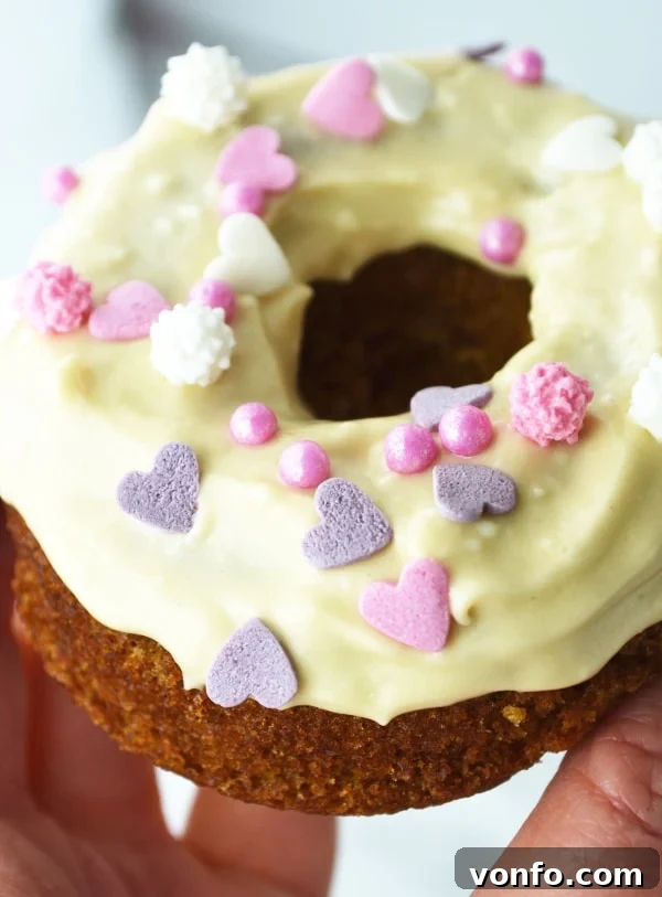 A trio of baked carrot cake doughnuts with maple cream cheese frosting and colourful sprinkles on a white plate. www.insidetherustickitchen.com