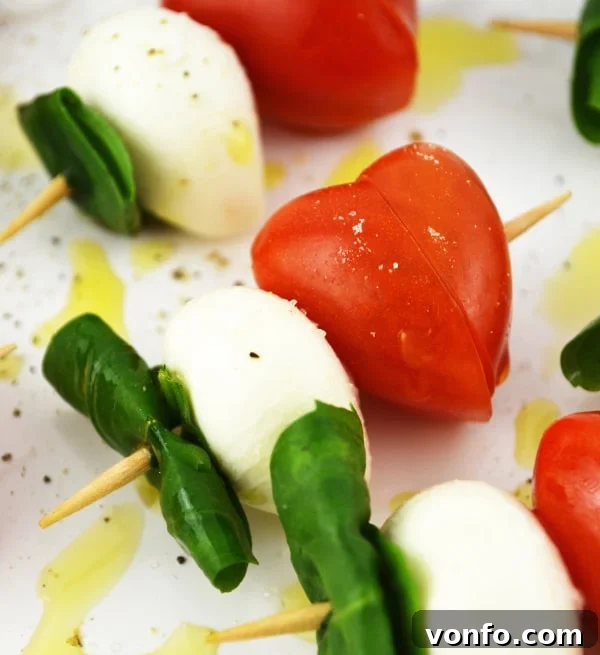 Close-up of heart-shaped tomatoes on Caprese skewers, showing the simple yet elegant presentation of this Valentine's appetizer.