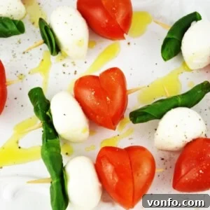 A close-up view of a Caprese Skewer, featuring a heart-shaped tomato, fresh mozzarella, and a basil leaf, signifying a quick and romantic appetizer.