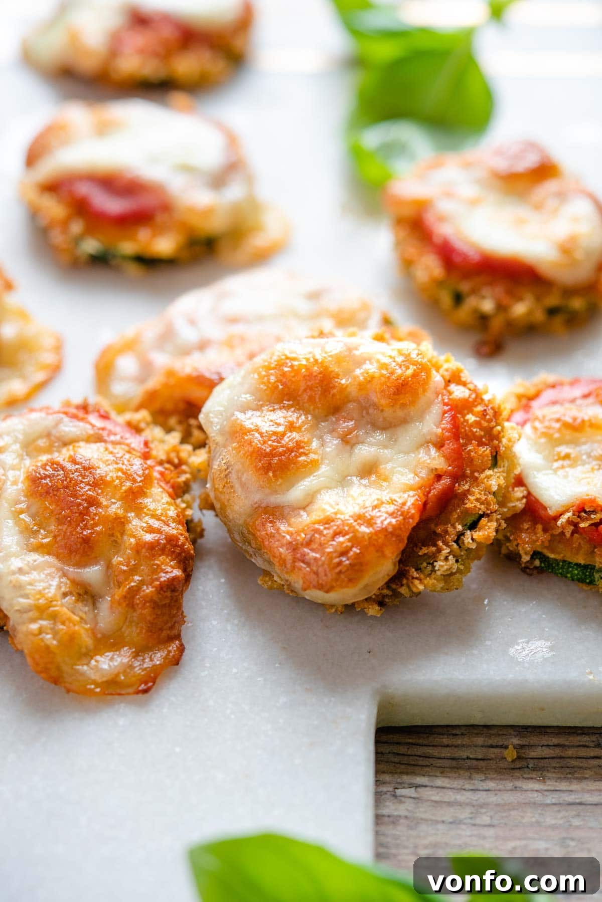 Golden Zucchini Pizza Fritters 6 A close up shot of a single fried zucchini pizza bite, showing its crispy breading, melted mozzarella, and tomato sauce, tempting to eat.