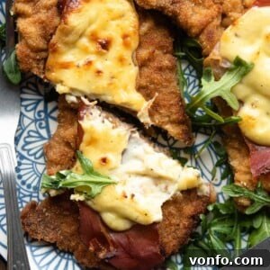 A close up of a veal cutlet cut in half topped with prosciutto and parmesan cream