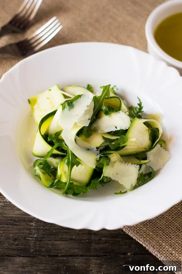 Close-up of freshly shaved Zucchini Ribbons with arugula, parmesan, and basil, ready to be dressed. A delightful summer salad idea from insidetherustickitchen.com