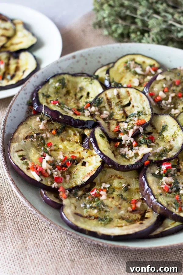 Grilled eggplant slices on a griddle pan, showing perfect char marks, preparing for the marinade.