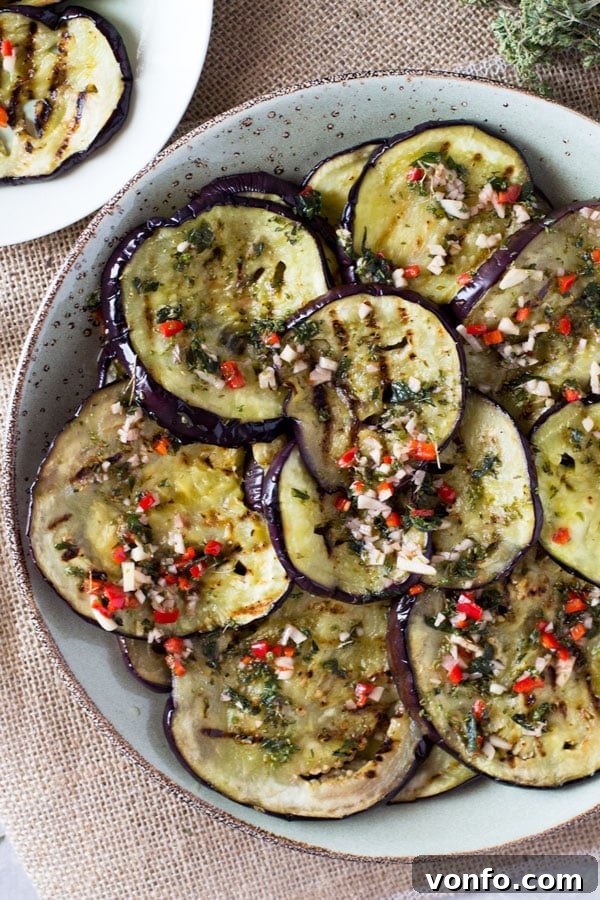 Close-up shot of Italian marinated eggplant served on a rustic wooden board with fresh herbs, ready to be enjoyed.