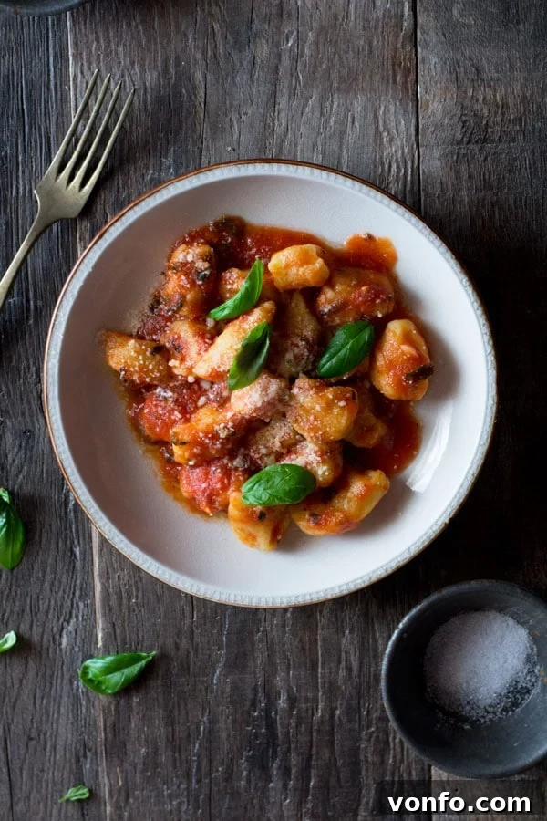Light and soft gnocchi with fresh tomato sauce recipe with ripe tomatoes, oregano, and garlic. Simple, easy, and authentic Italian tomato sauce for gnocchi and pasta. Gnocchi with fresh tomato sauce served in a rustic kitchen setting, showcasing the vibrant red sauce and soft gnocchi