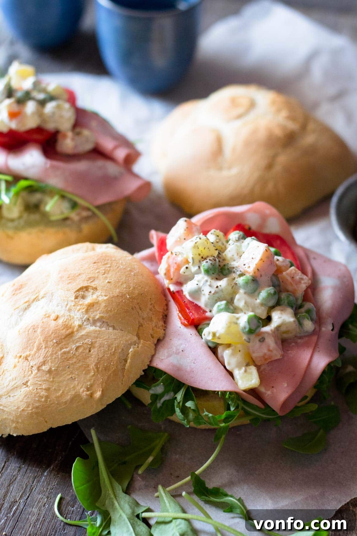 Effortless Classic Russian Salad 5 A close-up shot of creamy Russian salad served on a fresh bread roll, highlighting its texture and vibrant ingredients.