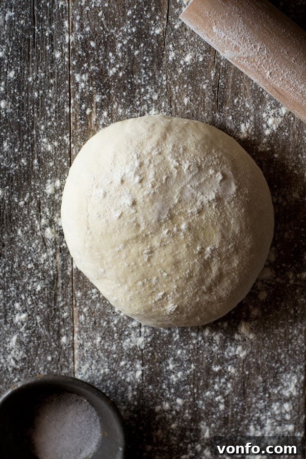 An overhead shot of raw yeast-free pizza dough on a wooden board