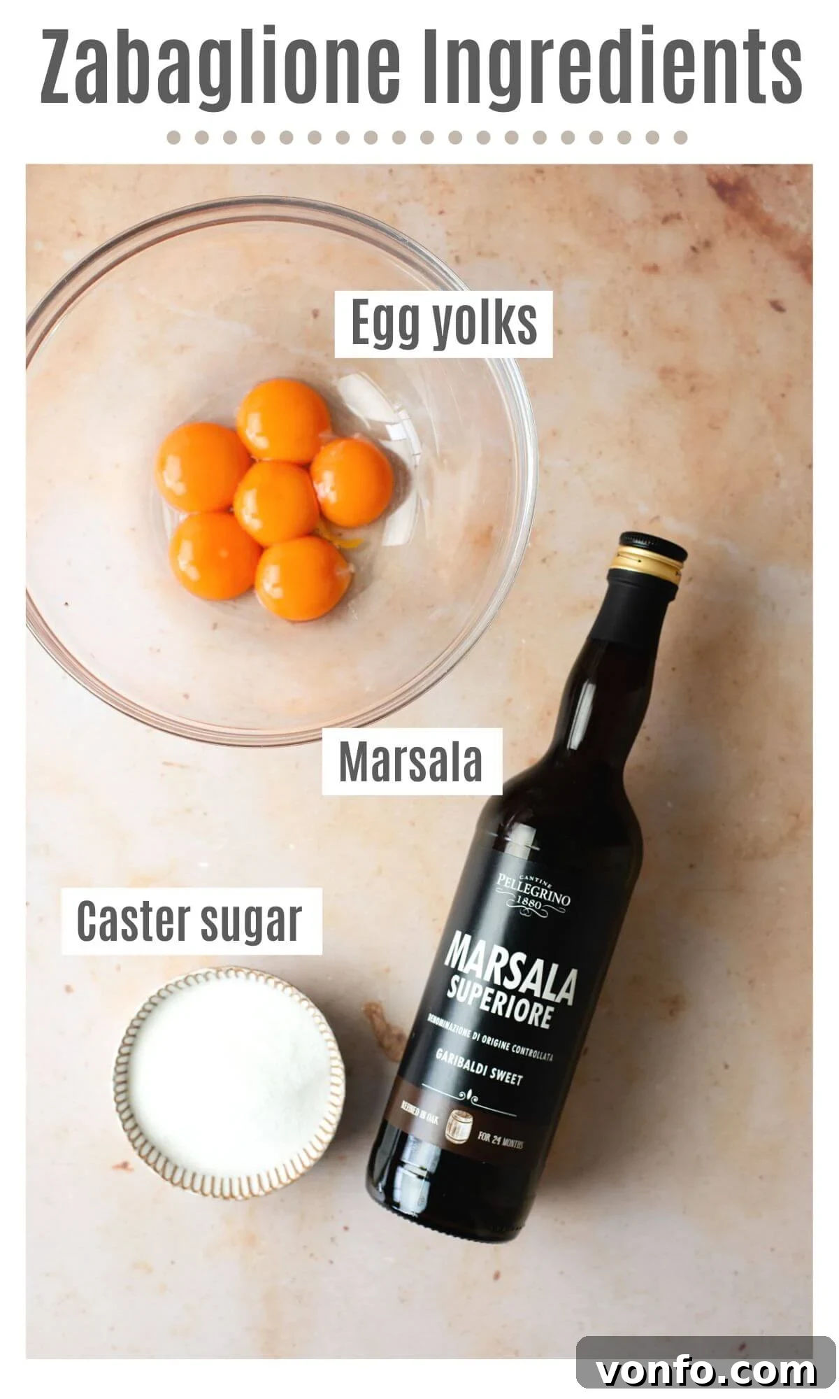 An overhead shot of essential Zabaglione ingredients: fresh egg yolks, sweet Marsala wine, and sparkling caster sugar, neatly arranged.