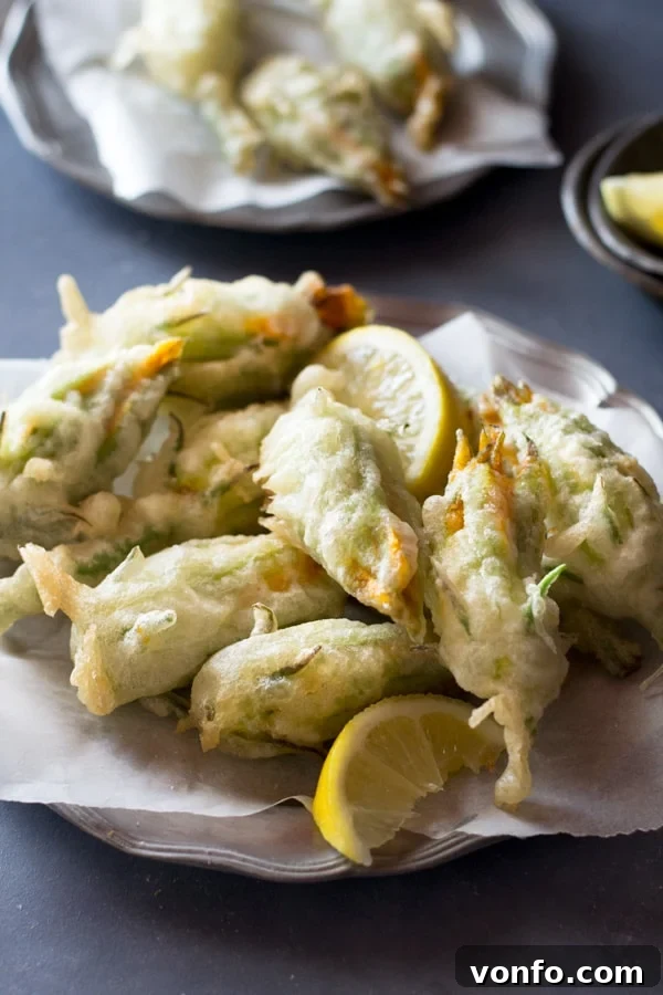 Crispy, deep fried ricotta stuffed zucchini flowers with lemon and chili flakes. An easy, elegant and fun Italian appetizer that's hard to resist. How to fry zucchini flowers and recipe at Inside the rustic kitchen - authentic Italian recipes. Close-up of crispy fried zucchini flowers stuffed with ricotta, chili flakes and lemon, showcasing the golden batter and vibrant filling.