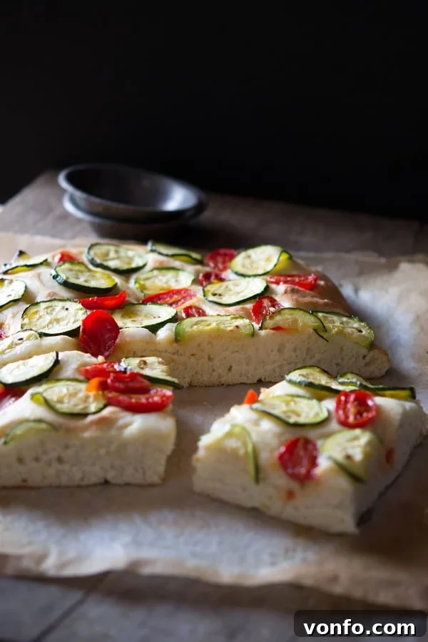 Homemade Zucchini Tomato Focaccia: A Simple and Flavorful Italian Treat Close-up of baked Zucchini Tomato Focaccia with visible dimples, crispy edges, and golden-brown crust.