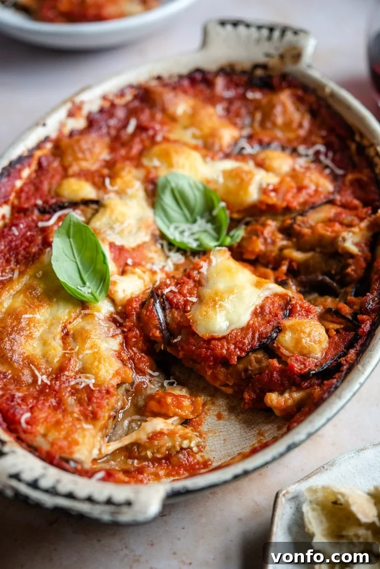 Parmigiana di Melanzane - Eggplant Parmigiana A side shot of freshly baked Eggplant Parmigiana in a rustic ceramic serving dish, showing melted cheese and layers