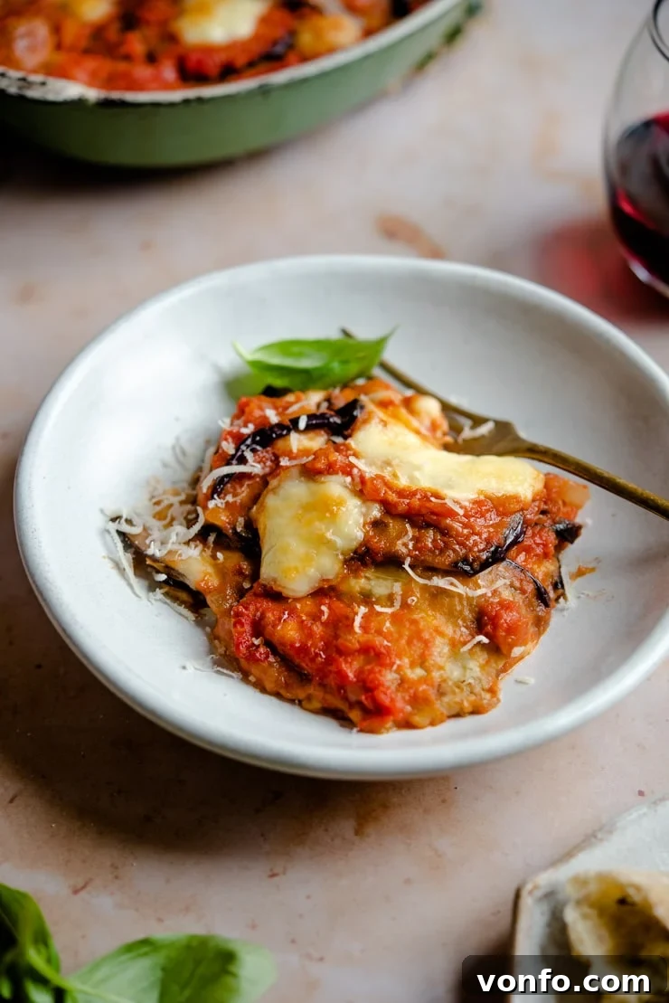 Delicious Eggplant Parmigiana Serving A close-up of a serving of Eggplant Parmigiana in a rustic bowl with a fork, showing the delicious layers
