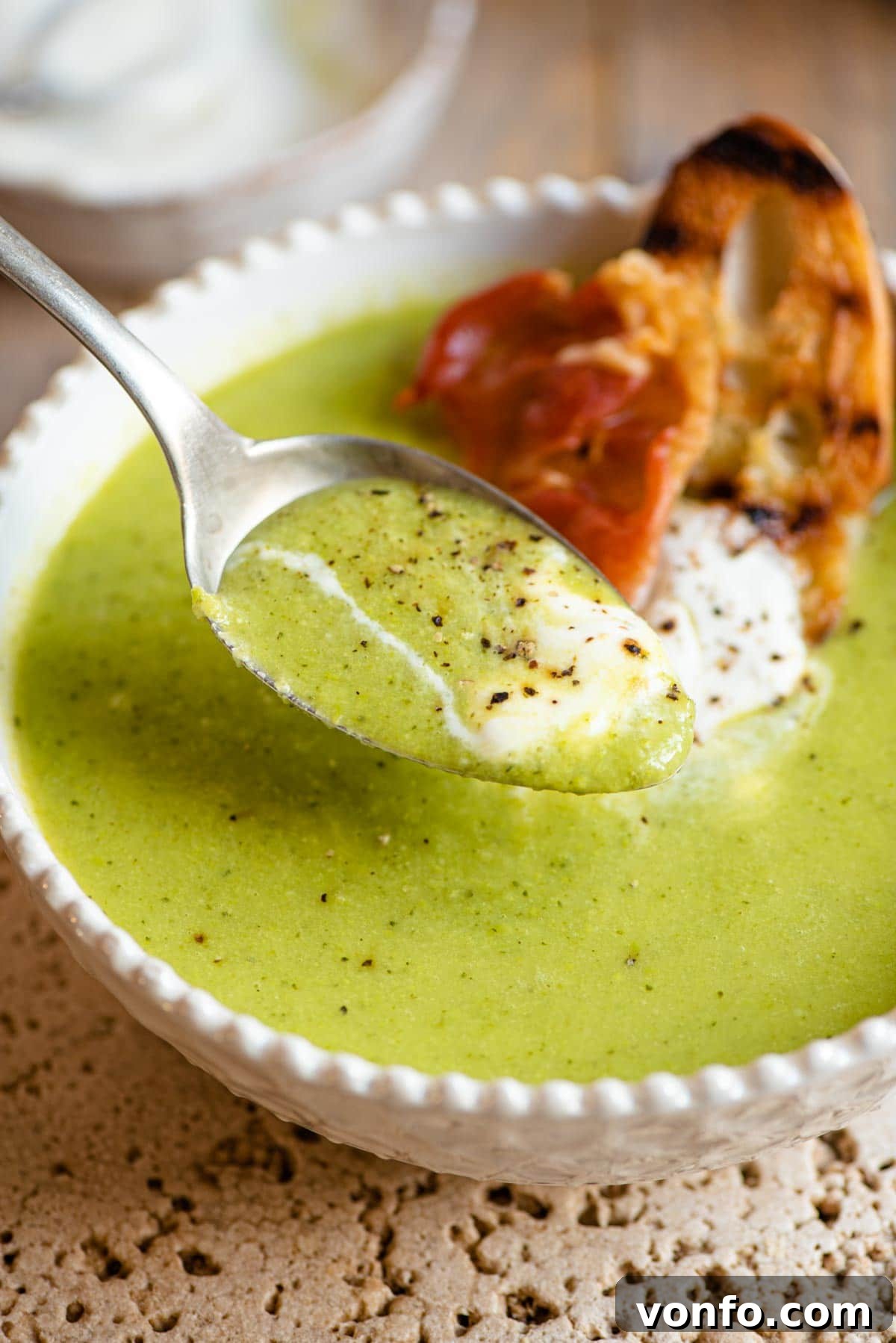 Silky Green Pea Soup with Prosciutto Crisps 6 A close-up shot of a spoonful of creamy green pea soup, highlighting its smooth texture and vibrant color.