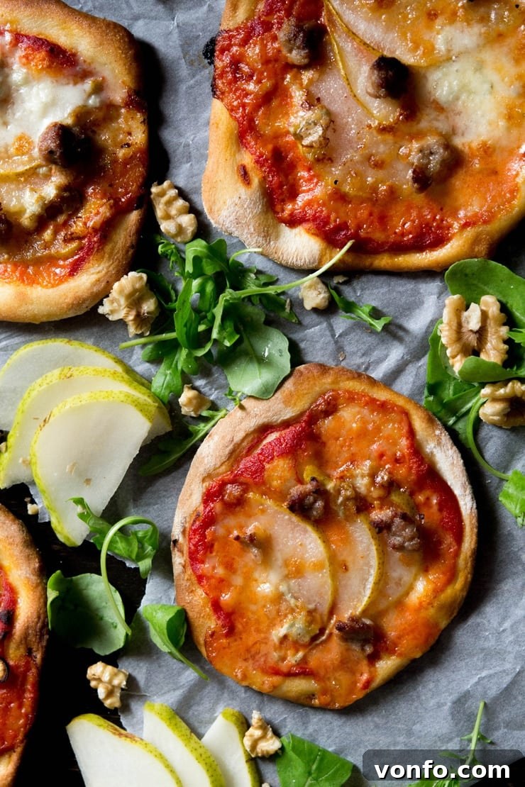 An overhead photo of mini sausage pizzas with pear, gorgonzola and arugula