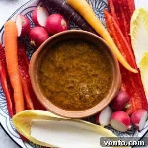 Bagna Cauda in a terracotta dish with raw vegetables all around.