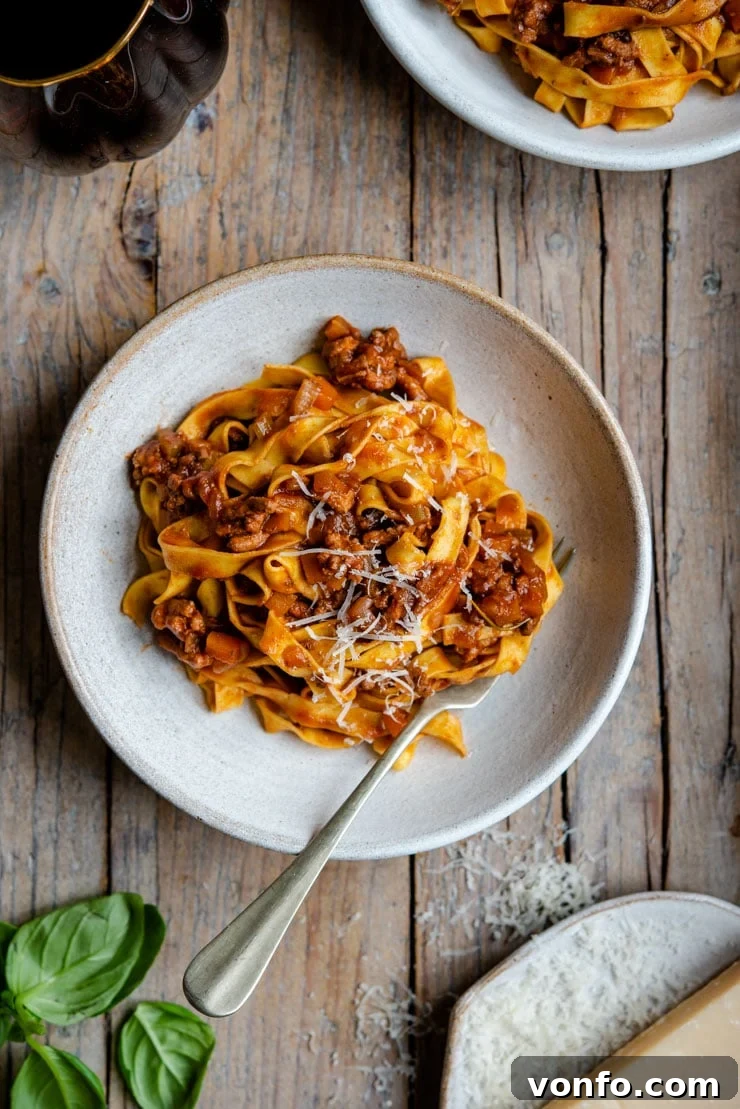 Authentic Italian Beef Ragu Ready to Serve An inviting overhead shot showcasing a rustic ceramic bowl generously filled with authentic Italian beef ragu, beautifully garnished with fresh basil leaves.