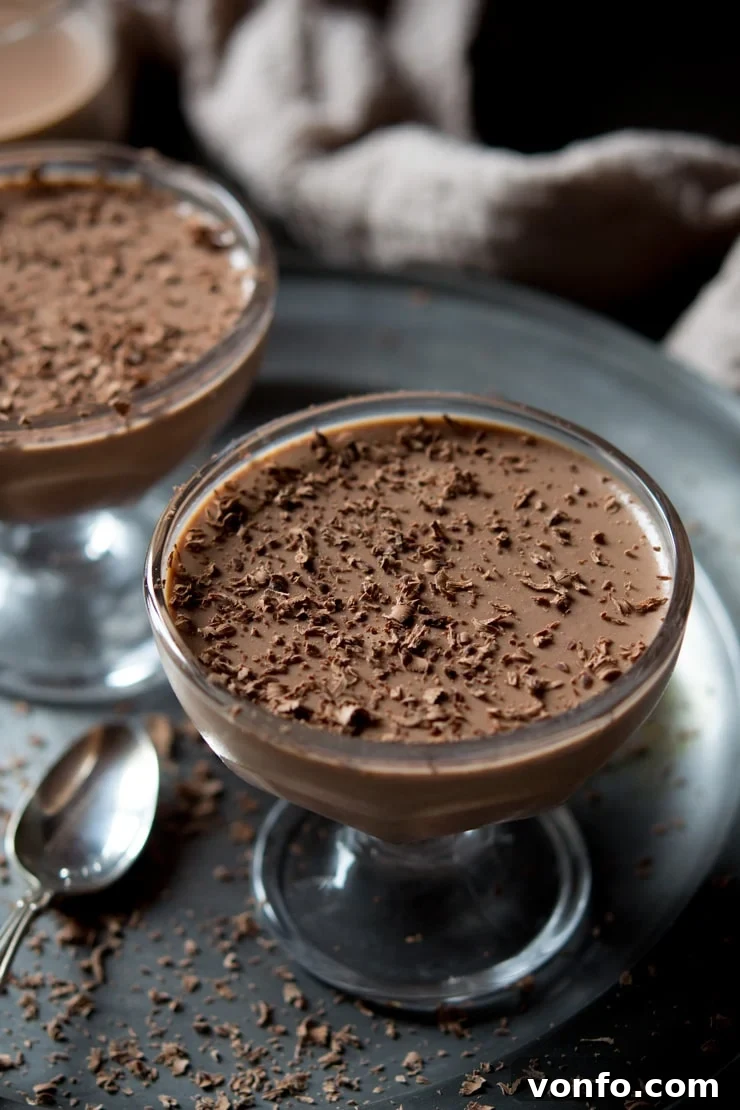 Close up of chocolate panna cotta in a glass bowl topped with grated chocolate.