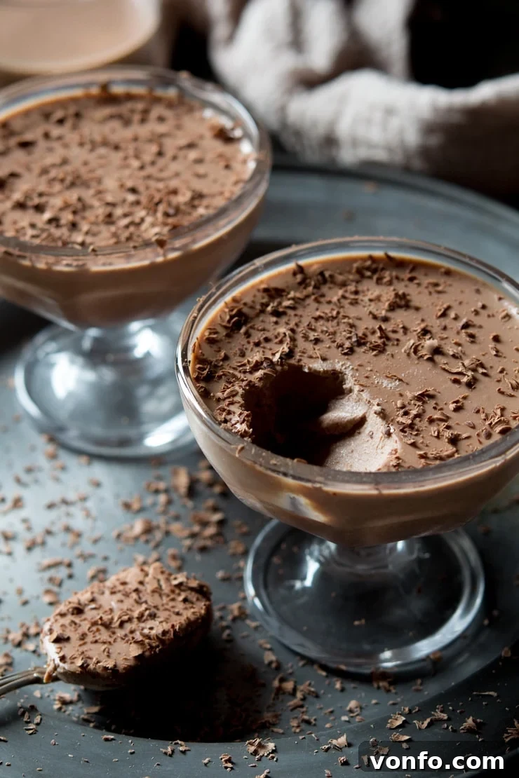 A close up of chocolate panna cotta with a spoonful of panna cotta in the background