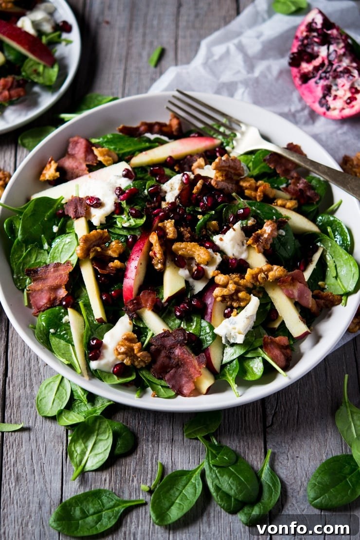 Gourmet Winter Salad with Spinach, Apple, Gorgonzola and Candied Walnuts A vibrant winter salad featuring spinach, gorgonzola cheese, red apple, and candied walnuts, artfully arranged