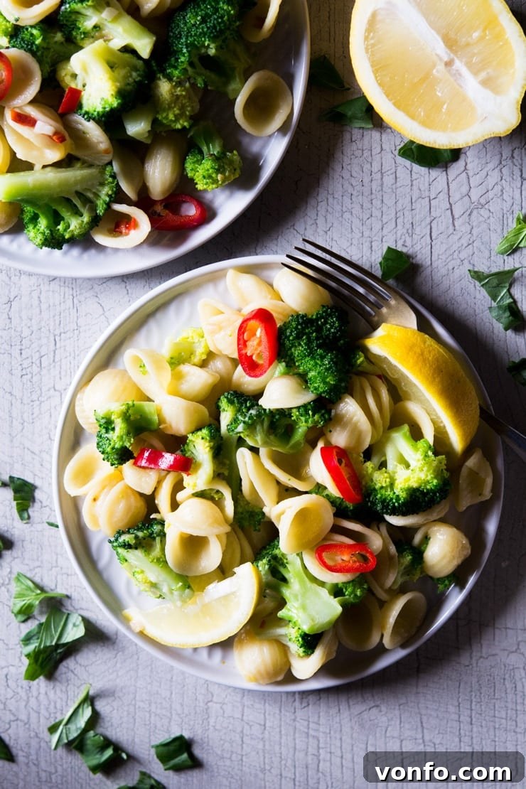 Garnished Orecchiette Broccoli Pasta A close up of broccoli pasta on a plate with chopped fresh chilli and lemon scattered over the top, highlighting the fresh garnishes and inviting presentation.