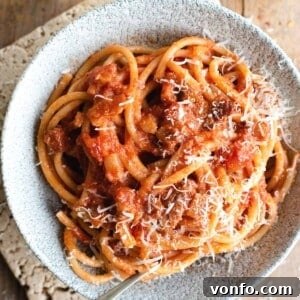 A close up of bucatini pasta in a bowl with amatriciana sauce