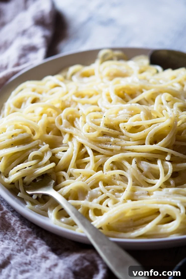 A side shot of a cacio e pepe recipe on a plate with a fork A side shot of a cacio e pepe recipe on a plate with a fork