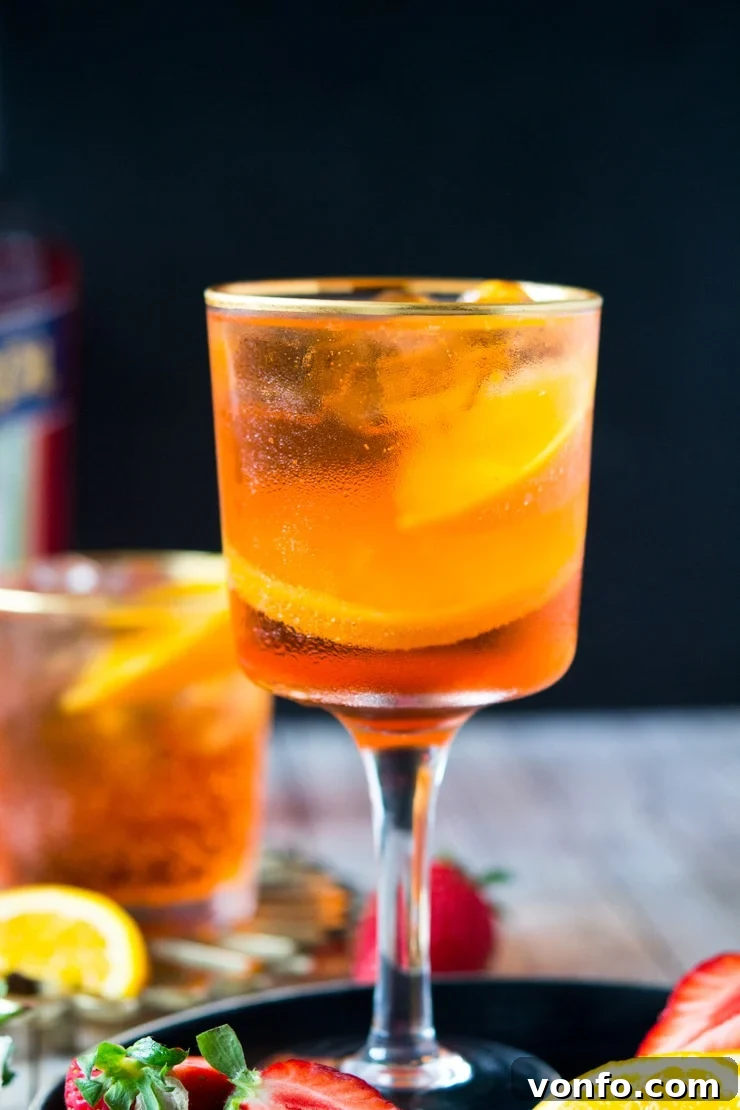 Refreshing Aperol Spritz with fruit garnish A close-up of a perfectly crafted Aperol Spritz cocktail in a glass, with vibrant orange slices and fresh strawberries enhancing its visual appeal.