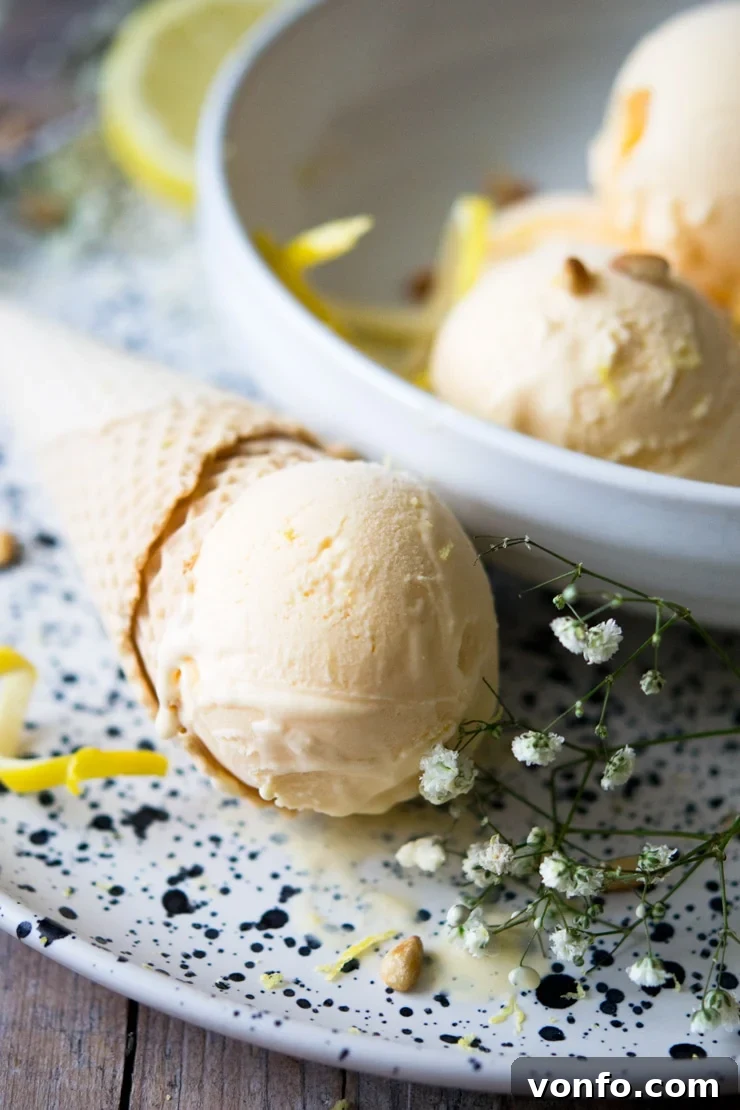 Amalfi Lemon Limoncello Gelato 6 A close-up, mouth-watering shot of a perfect scoop of golden Lemon Ice Cream delicately placed on a crisp, classic ice cream cone, emphasizing its rich, smooth texture and inviting appeal.