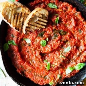 Authentic Italian Tomato Sauce Effortlessly Delicious 4 A close up overhead shot of tomato sauce in a skillet with two slices of char-grilled bread at the side.