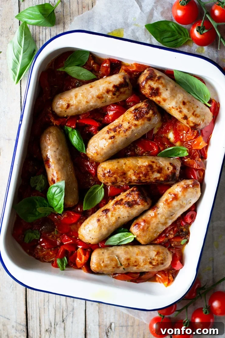 An overhead shot of a one pot Italian sausage bake with tomatoes and peppers, garnished with fresh basil leaves