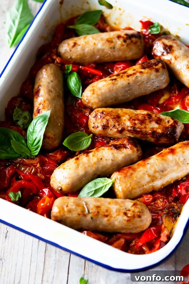 A close up of an Italian sausage bake with tomatoes and basil leaves, ready to serve