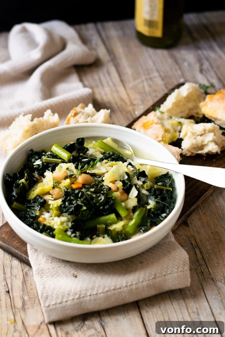 Tuscan Minestrone Soup: A hearty and comforting bowl of soup made with green vegetables and rice. This minestrone is so easy, delicious and perfect for a rainy day. | Italian Minestrone Soup | Authentic Italian Recipes | Italian Soup A bowl of Tuscan minestrone soup on a wooden surface with crusty bread
