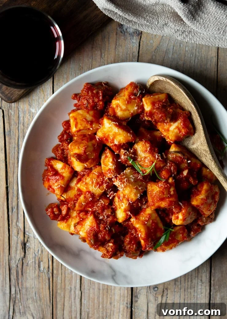 Simple Sausage Ragu, Sublime Ricotta Gnocchi 3 An inviting overhead shot of a generous serving of homemade sausage ragu beautifully tossed with fluffy ricotta gnocchi in a large white bowl, ready to be savored.