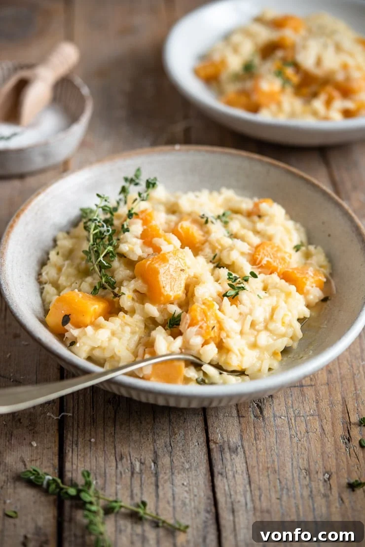 Delicious and Creamy Butternut Squash Risotto Recipe | Italian Comfort Food A side shot of butternut squash risotto in a rustic bowl topped with fresh thyme, showing its creamy texture.