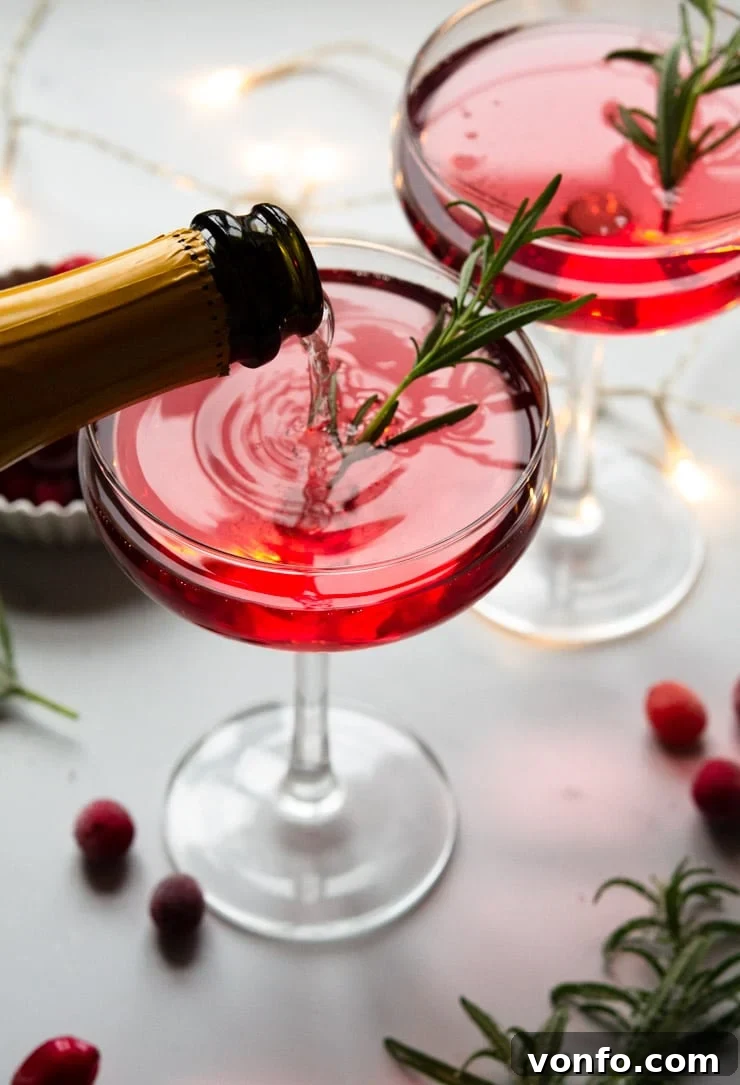 Someone pouring a Christmas cocktail topped with rosemary