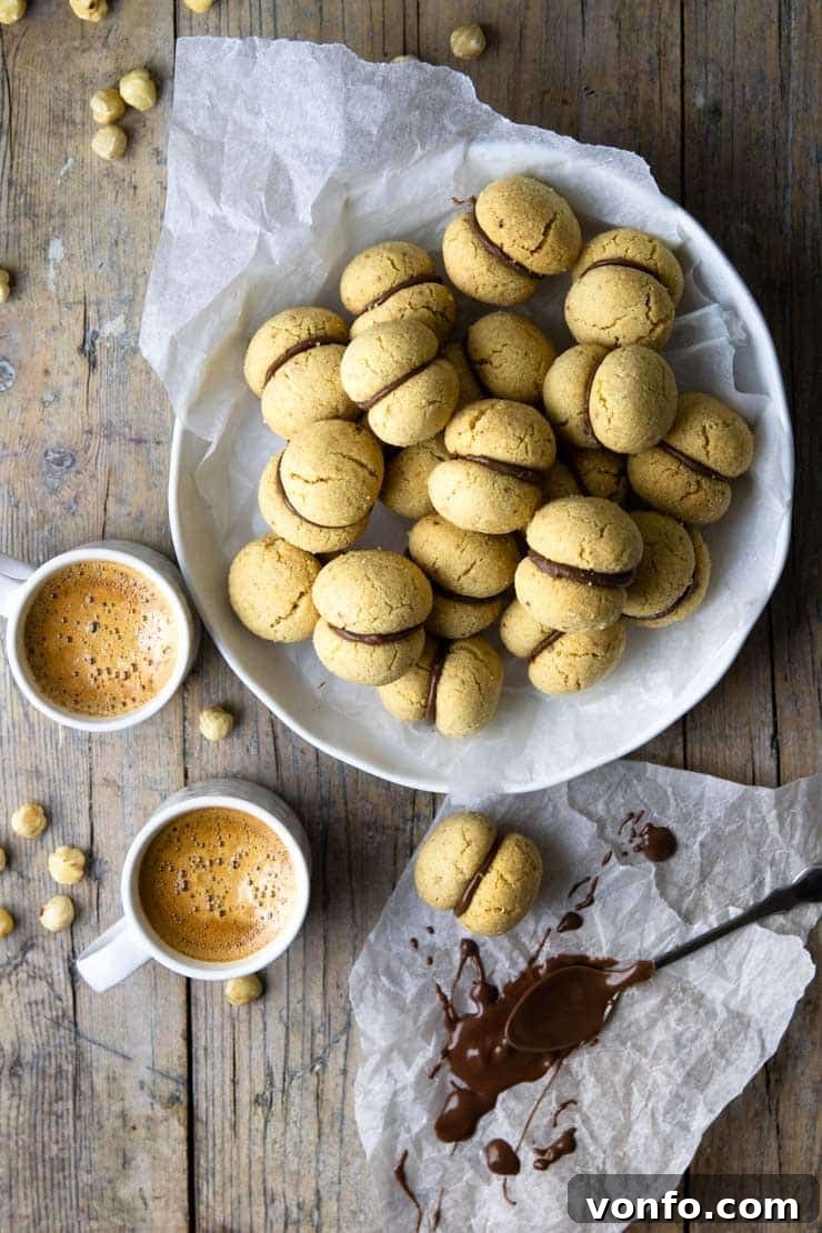 An overhead shot of Lady's Kisses cookies elegantly arranged in a large serving bowl, with two steaming cups of coffee subtly positioned to the side, highlighting their perfect pairing for a coffee break.