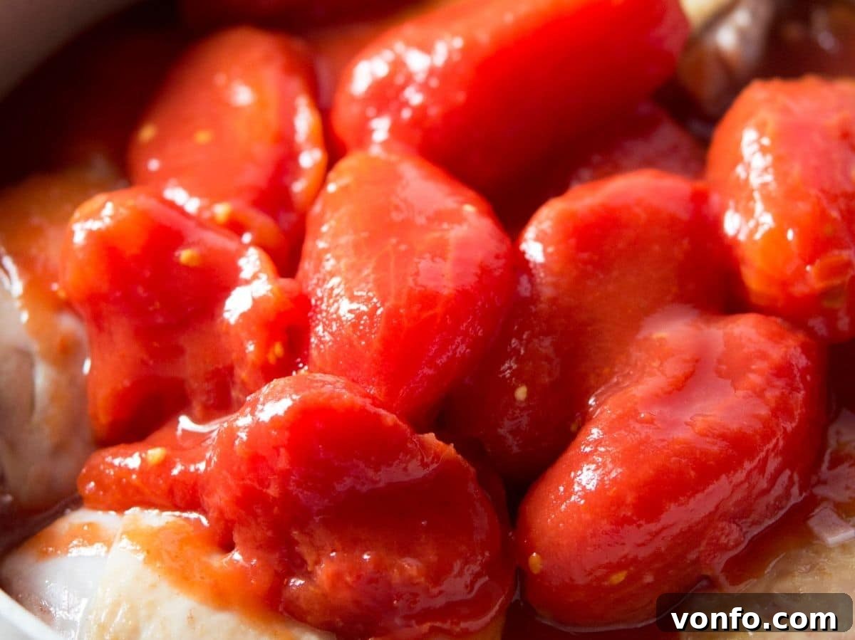 Unlocking Italian Flavors 3 A close up of canned plum tomatoes in a pot with chicken, showcasing their rich red color.