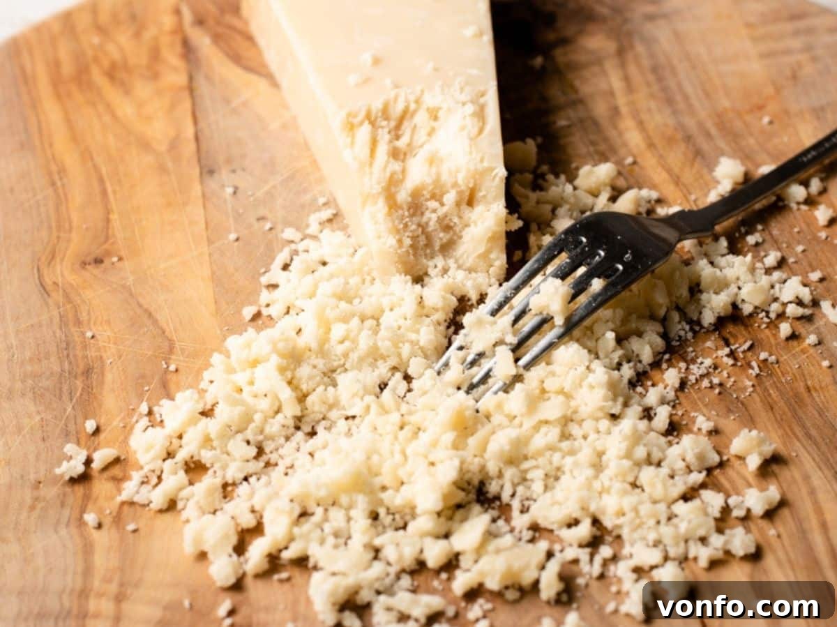 Unlocking Italian Flavors 5 A close up of Parmigiano Reggiano being crumbled with a fork, showing its crystalline texture.