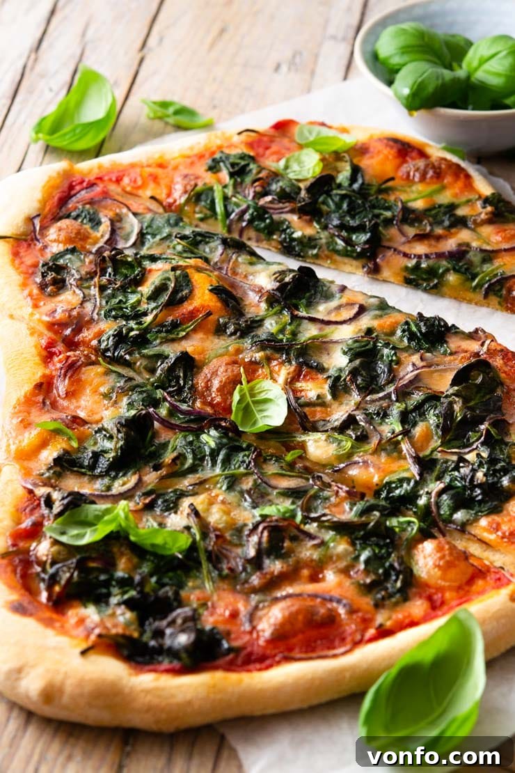 Sliced Spinach Pizza with Gorgonzola and Red Onion: Close-up of Crispy Crust and Melted Cheese A close-up of a delicious spinach pizza cut into perfect slices, showcasing the perfectly melted Gorgonzola and mozzarella cheese, soft wilted spinach, and thinly sliced red onion on a golden, crispy crust.