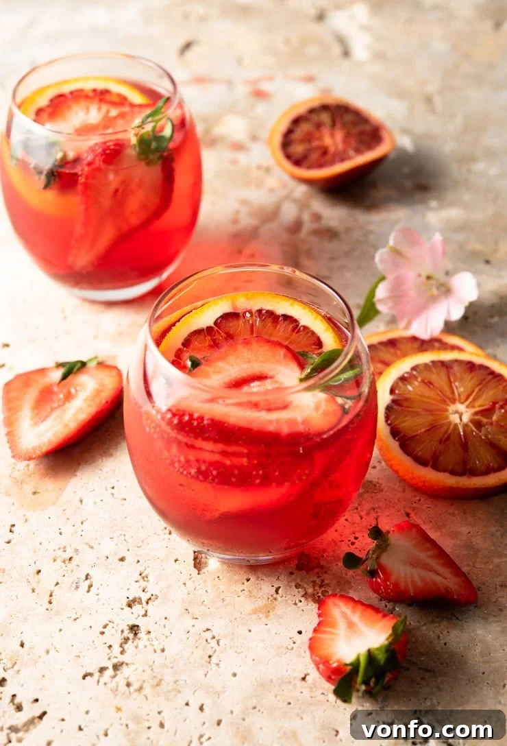 A vibrant and refreshing Classic Campari Spritz, garnished beautifully with strawberries and oranges, perfect for an Italian aperitivo. Two Campari Spritz cocktails in round glasses, garnished with fresh strawberries and orange slices, sitting on a table ready to be enjoyed as an aperitivo.