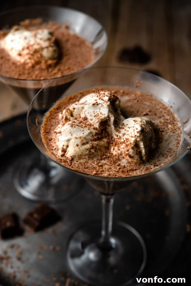 Close-up of Indulgent Chocolate Martini A mesmerizing close-up of a chocolate martini, elegantly topped with a generous swirl of fluffy whipped cream and delicate chocolate shavings, highlighting its rich texture.