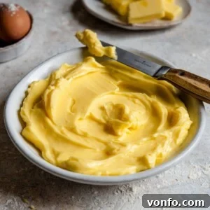 A close up side shot of softened butter in a bowl with a knife at the side.