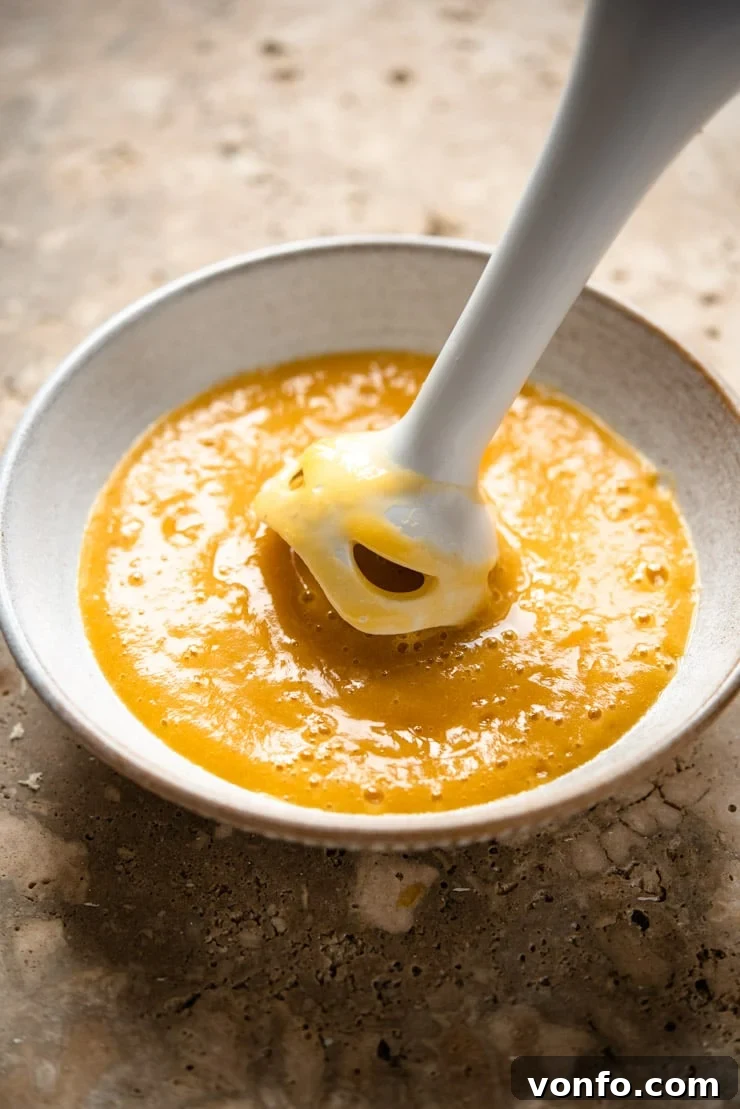 A close-up shot capturing the process of making smooth peach puree, showcasing the ideal texture achieved for crafting the perfect Peach Bellini cocktail.