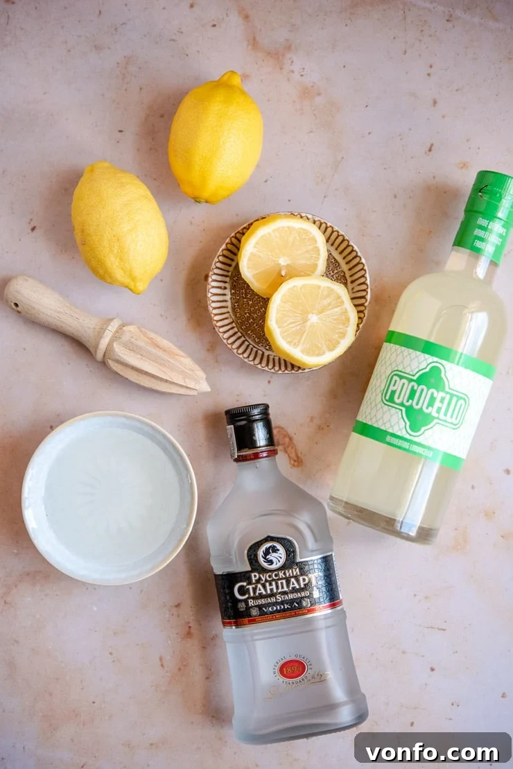 Ingredients laid out to make a Limoncello Martini, including lemons, a bottle of limoncello, vodka, and simple syrup