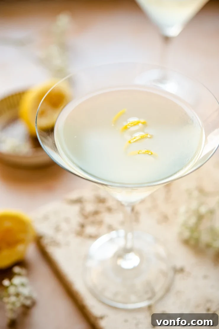 Close up of a vibrant Limoncello Martini in a classic martini glass, garnished with a lemon twist