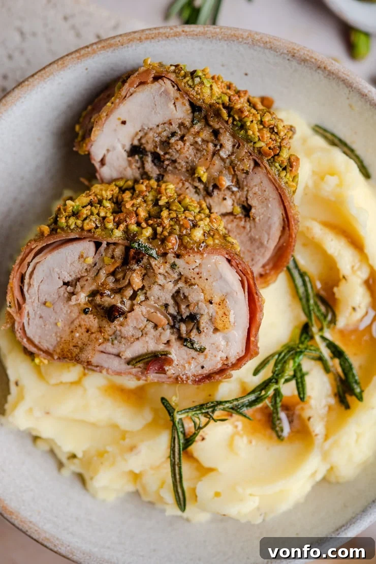 Close-up of Stuffed Pork Tenderloin: A perfect slice revealing the flavorful layers. A close-up shot of a slice of stuffed pork tenderloin sitting on top of mashed potatoes, showing the beautiful spiral of stuffing and crust.