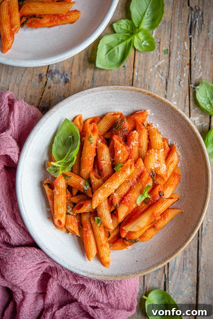 An overhead shot of Penne Pomodoro in a bowl with fresh basil leaves, highlighting its fresh and inviting appearance