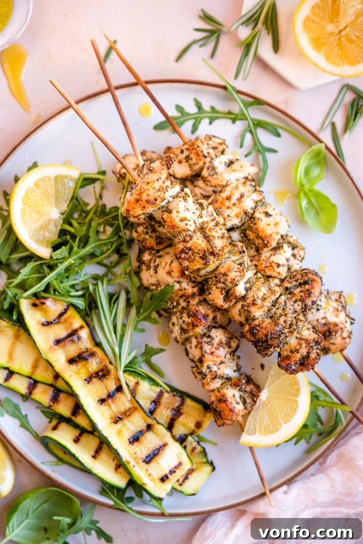 An overhead shot of chicken spiedini with grilled vegetables and arugula on the side, showcasing perfectly cooked Italian chicken skewers.