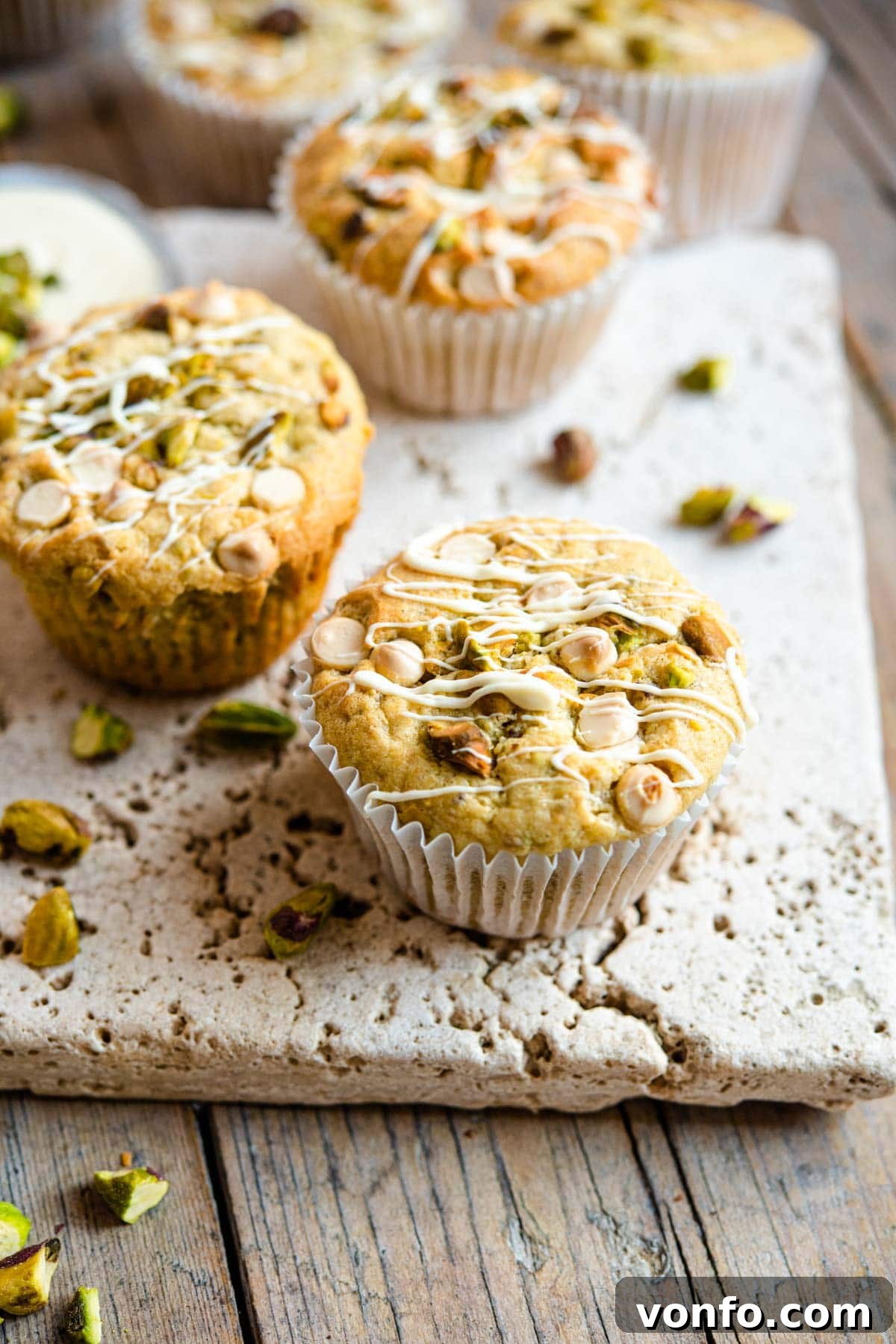 Pistachio White Chocolate Dream Muffins 2 A close up of a pistachio muffin topped with white chocolate chips, highlighting its soft texture and crunchy toppings