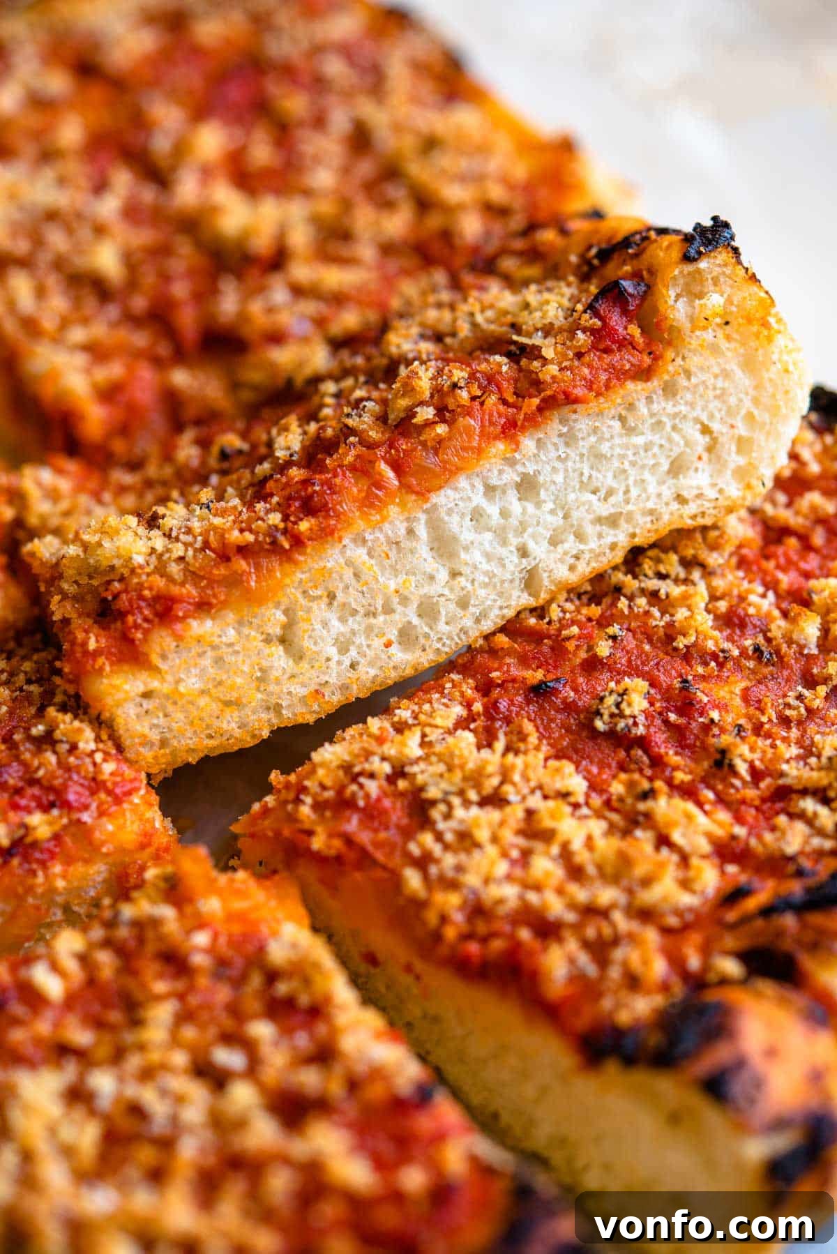 Sicilian Sfincione Pizza 3 A side shot of a thick, light, and airy pizza crust topped with rich tomato sauce, highlighting its sponge-like texture